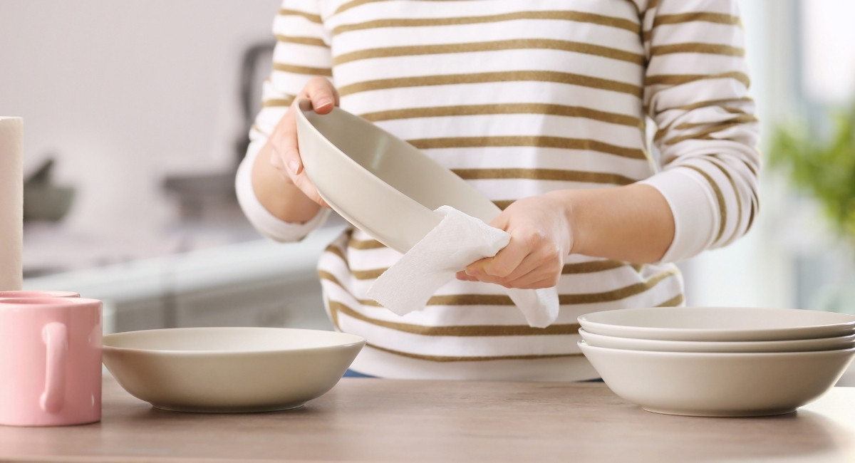 キッチンペーパーでお皿を拭く人の手元の写真