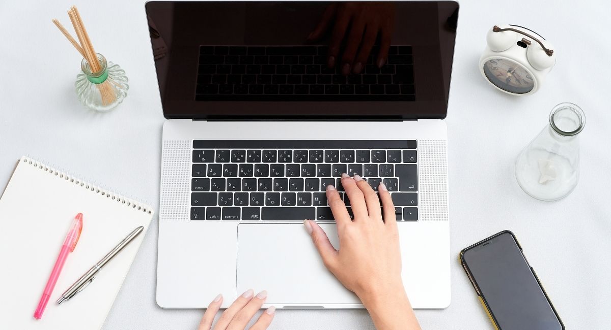ノートパソコンを操作している人の手元を俯瞰で撮った写真