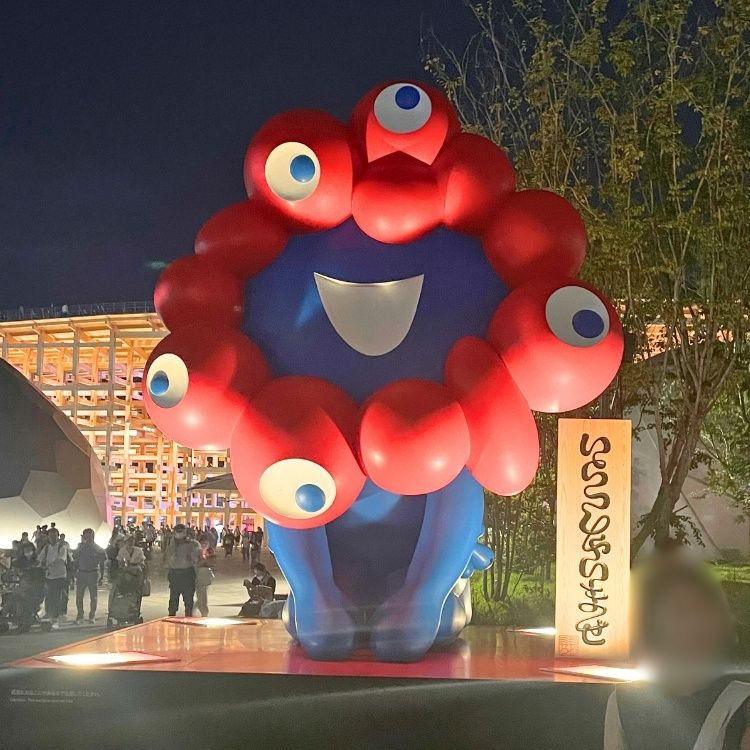 夜に撮影した「いらっしゃいませ」というミャクミャクの三つ指オブジェの写真