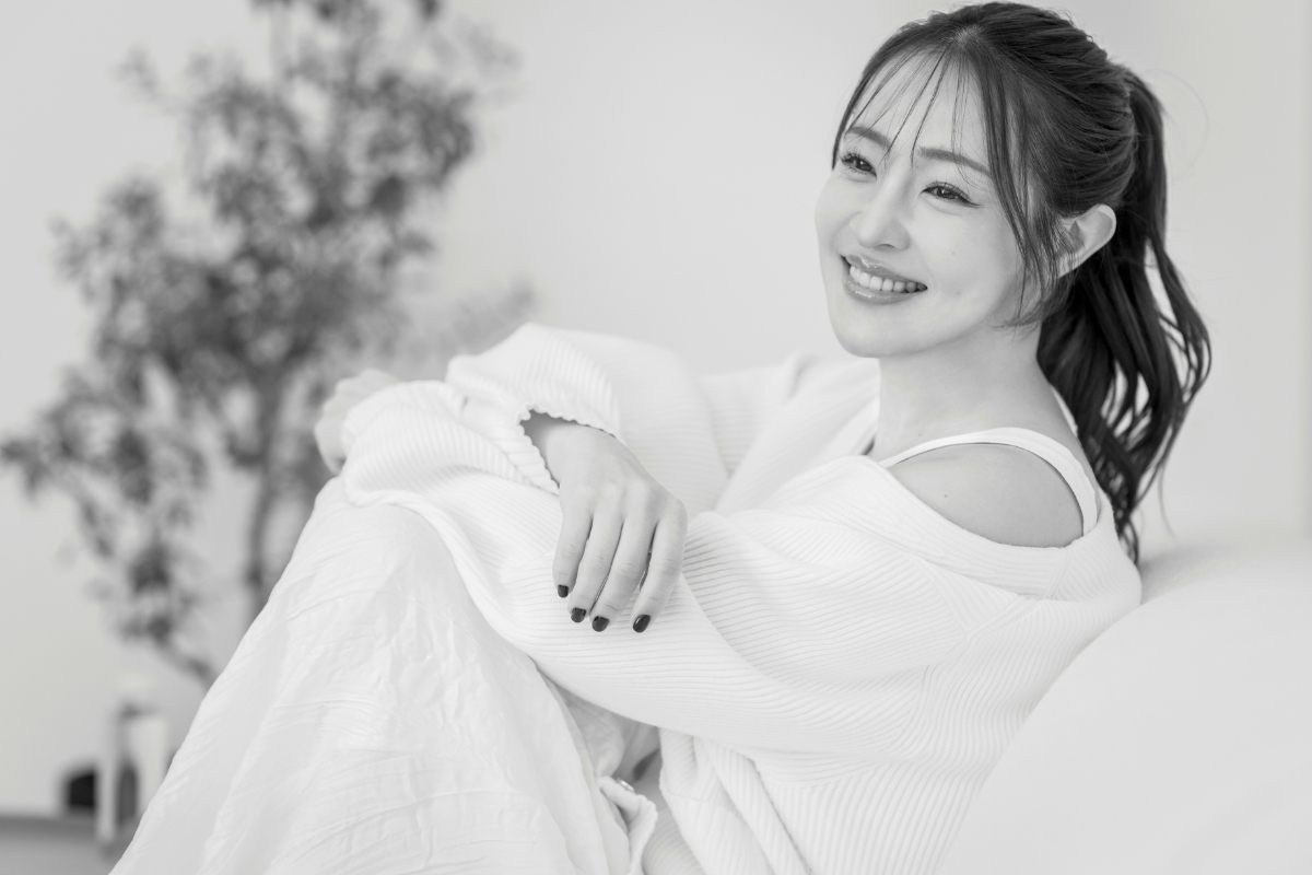 リラクシーなスタイルでソファに座るポニーテールの大沢さんの写真