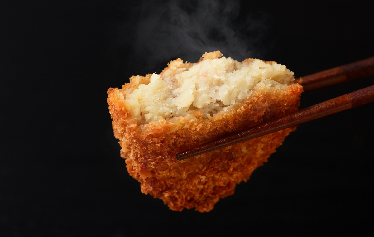 アツアツのコロッケをお箸で持ち上げている写真