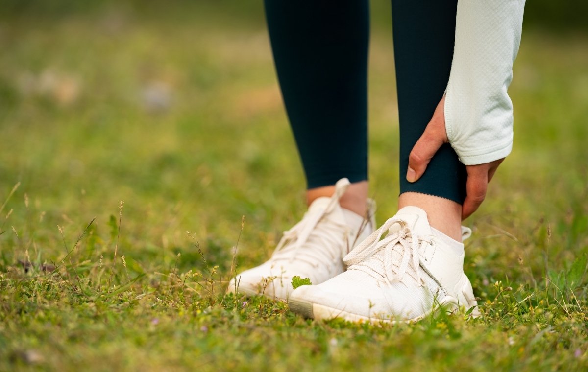 ジョギング中の女性が足首を押さえている写真