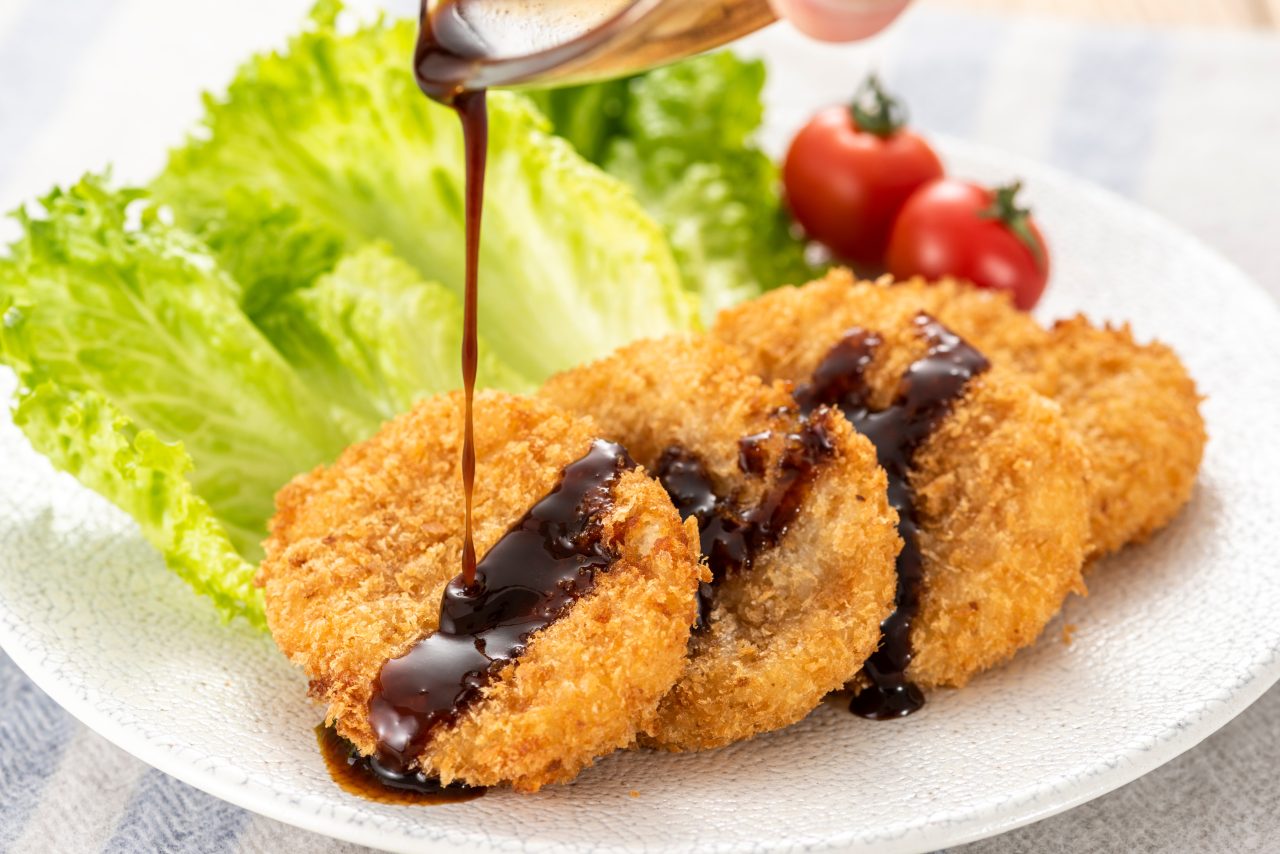 コロッケにソースをかけている写真