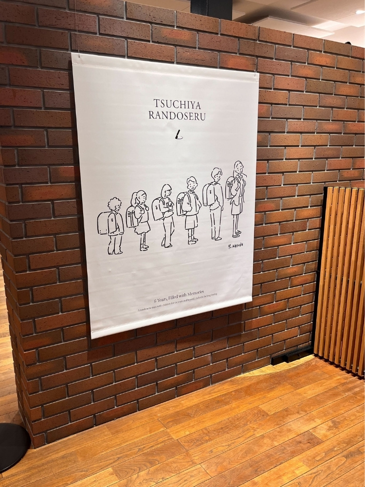 レンガ調の壁に貼られた、土屋鞄のタペストリーの写真